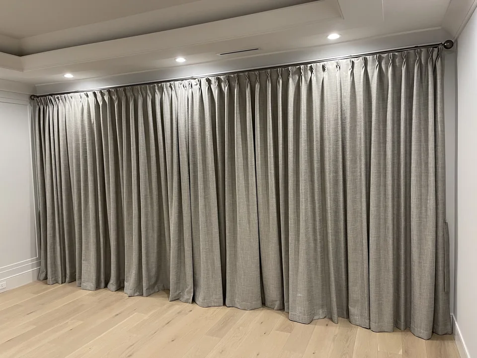 Neutral full-length drapery with repeated pleats across a wide window wall