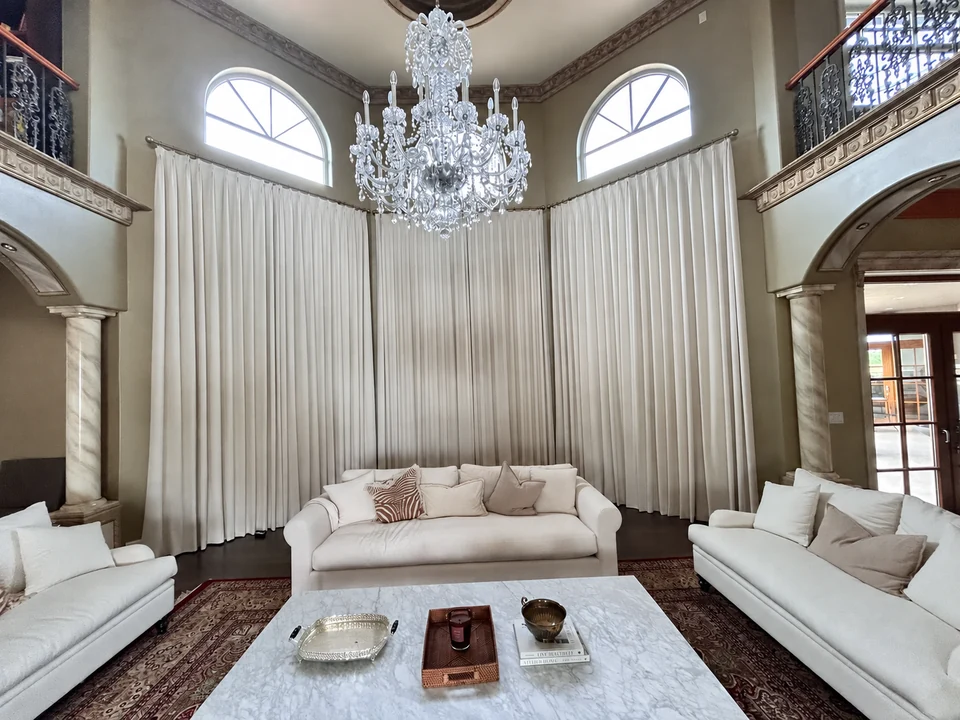 Full-height ivory curtains frame this double-height living room