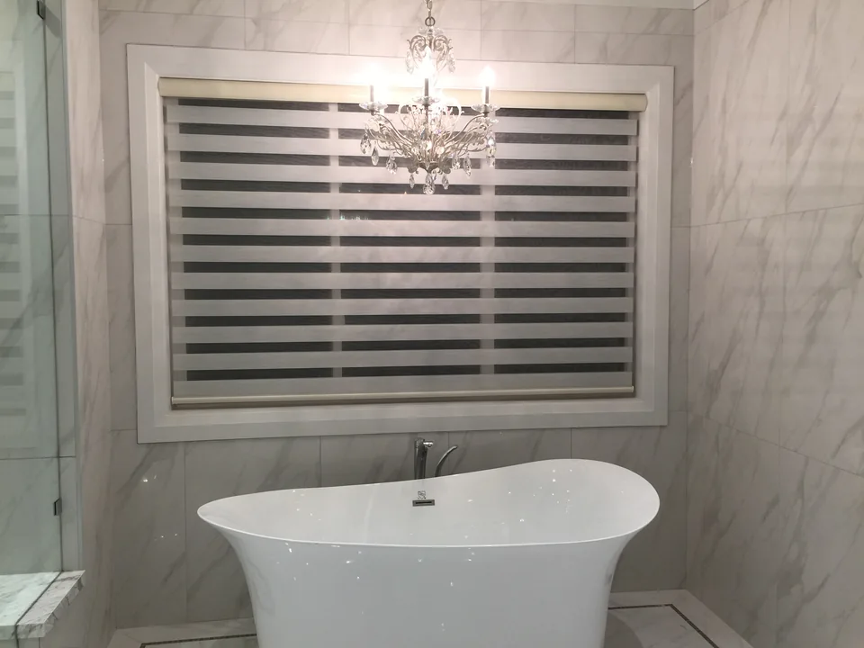 The same bathroom window with the shade bands in a different position, revealing alternating sheer and opaque sections