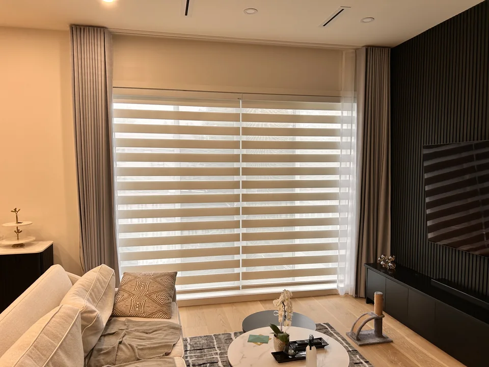 A zebra shade covers the glass while full-height drapery frames the opening