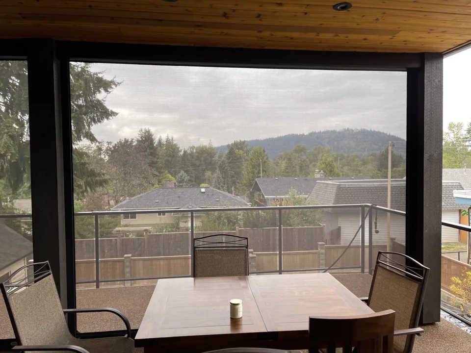 A closer view across the dining table shows the landscape through the outdoor screen mesh