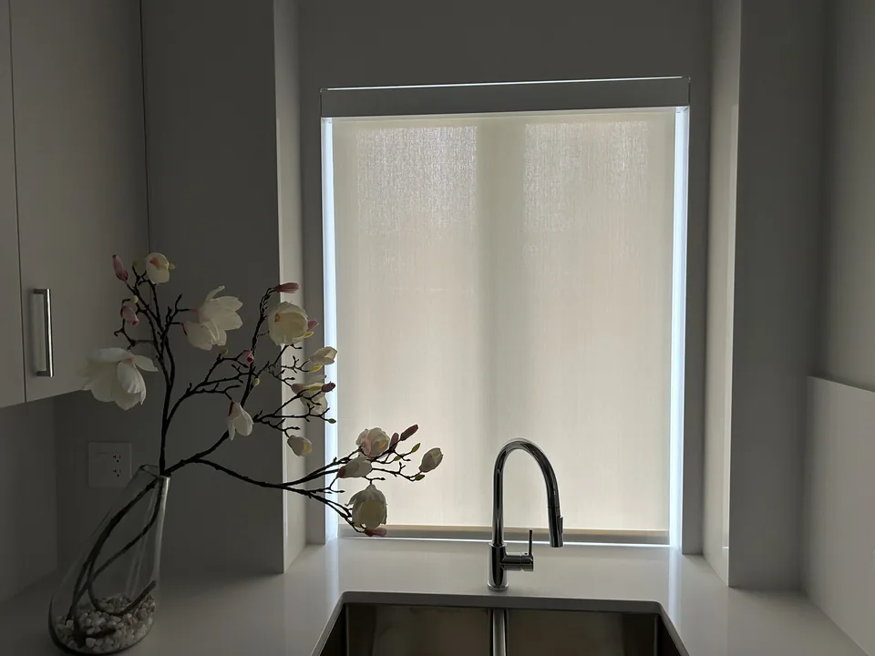 A roller shade fitted above the kitchen sink, with light passing through the fabric