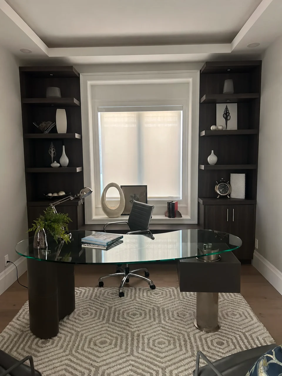 A roller shade sits within the window opening behind the desk, framed by built-in shelving