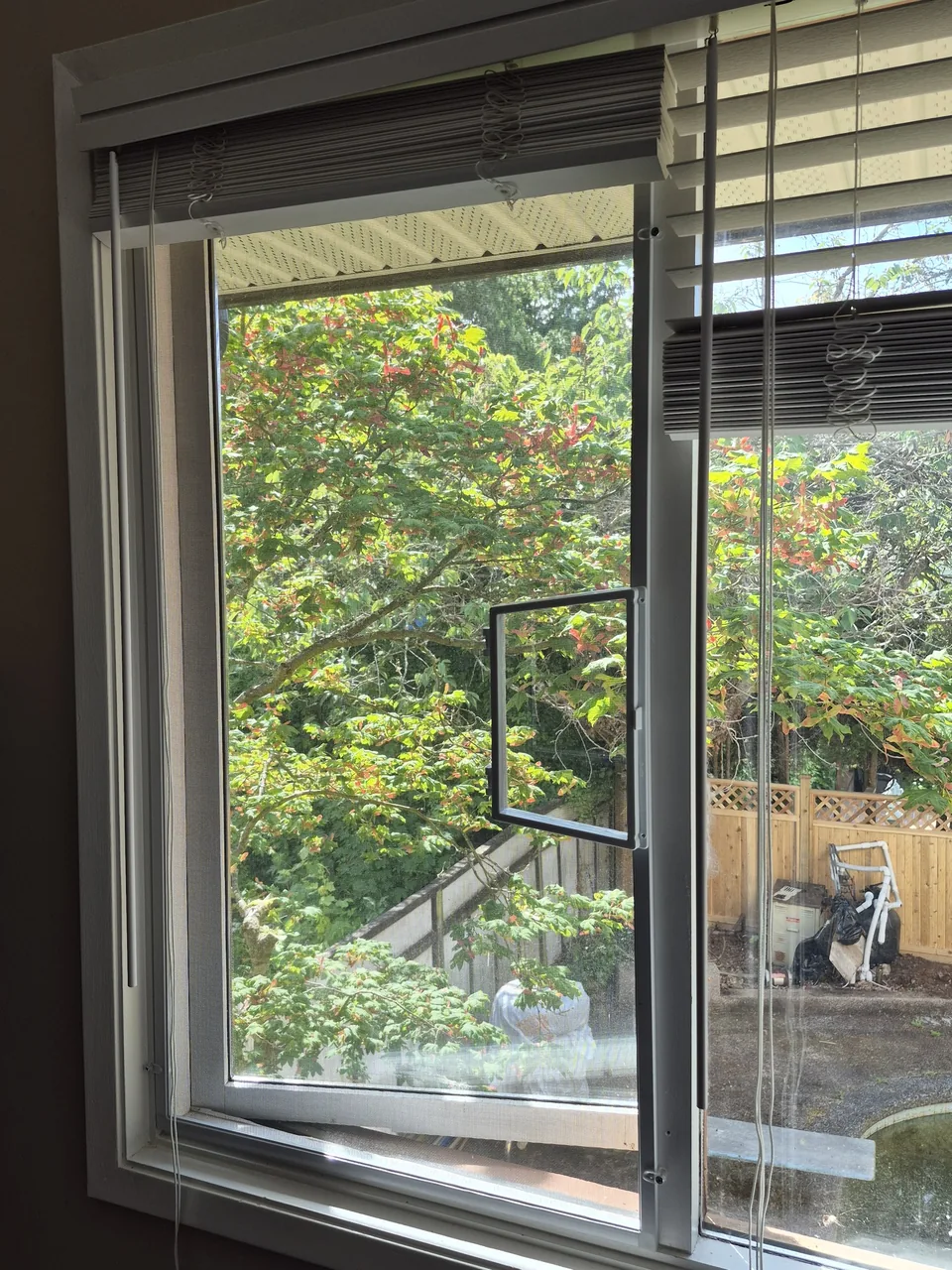 A framed mesh screen includes a small access flap beside the window hardware
