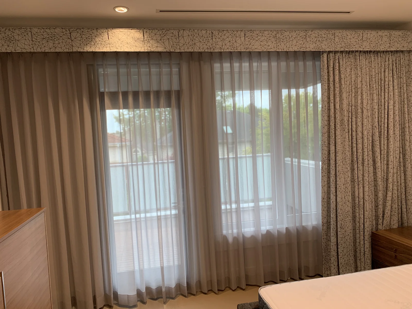 Full-length sheer curtains layered with patterned drapery and a matching pelmet