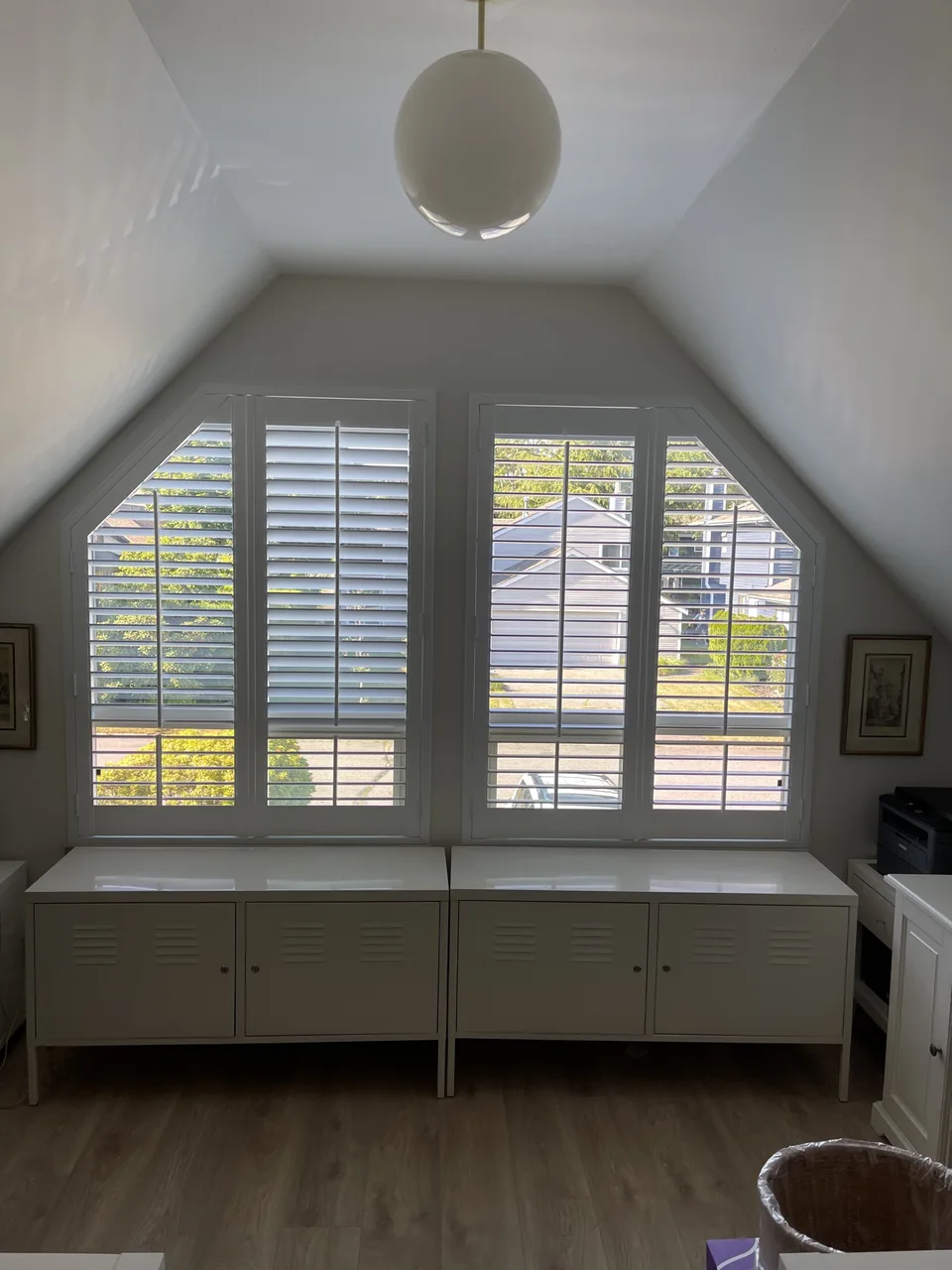 A pair of shutter-covered windows follows the sloping sides of the room, with the louvres shown in different positions
