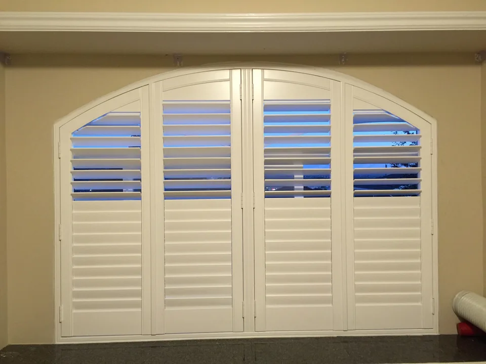 Several framed shutter panels follow the curved top of a wide opening