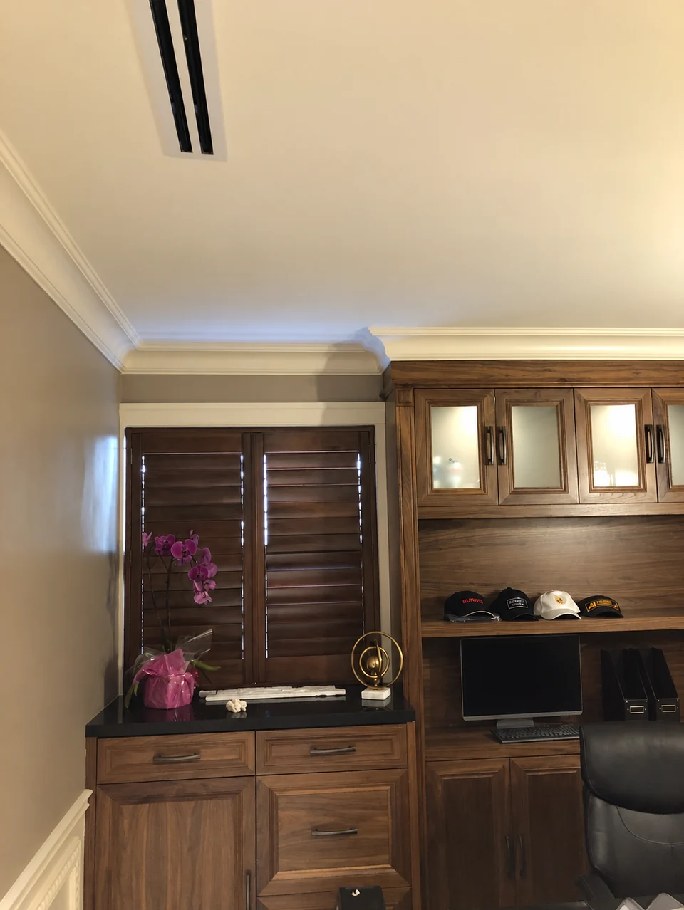 Dark wood-toned shutters sit above a fitted desk, echoing the surrounding cabinetry