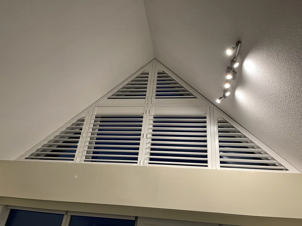 White shutter panels follow a triangular upper window, with rectangular panels below the peak