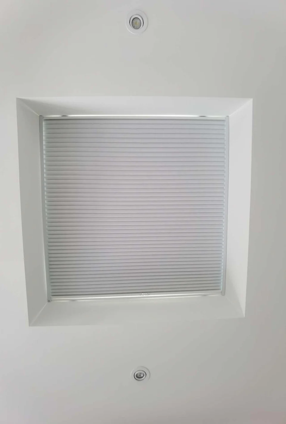 White pleated skylight shade within a recessed ceiling opening