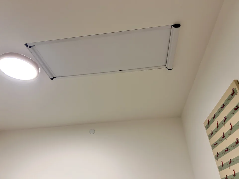 Manual retractable skylight roller shade with blackout fabric, shown closed, with a long operating handle on the left