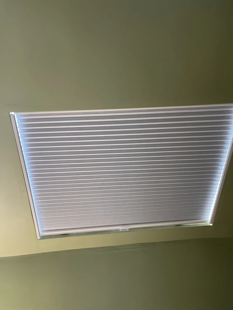 Pleated skylight shade with side channels and a central hand grip