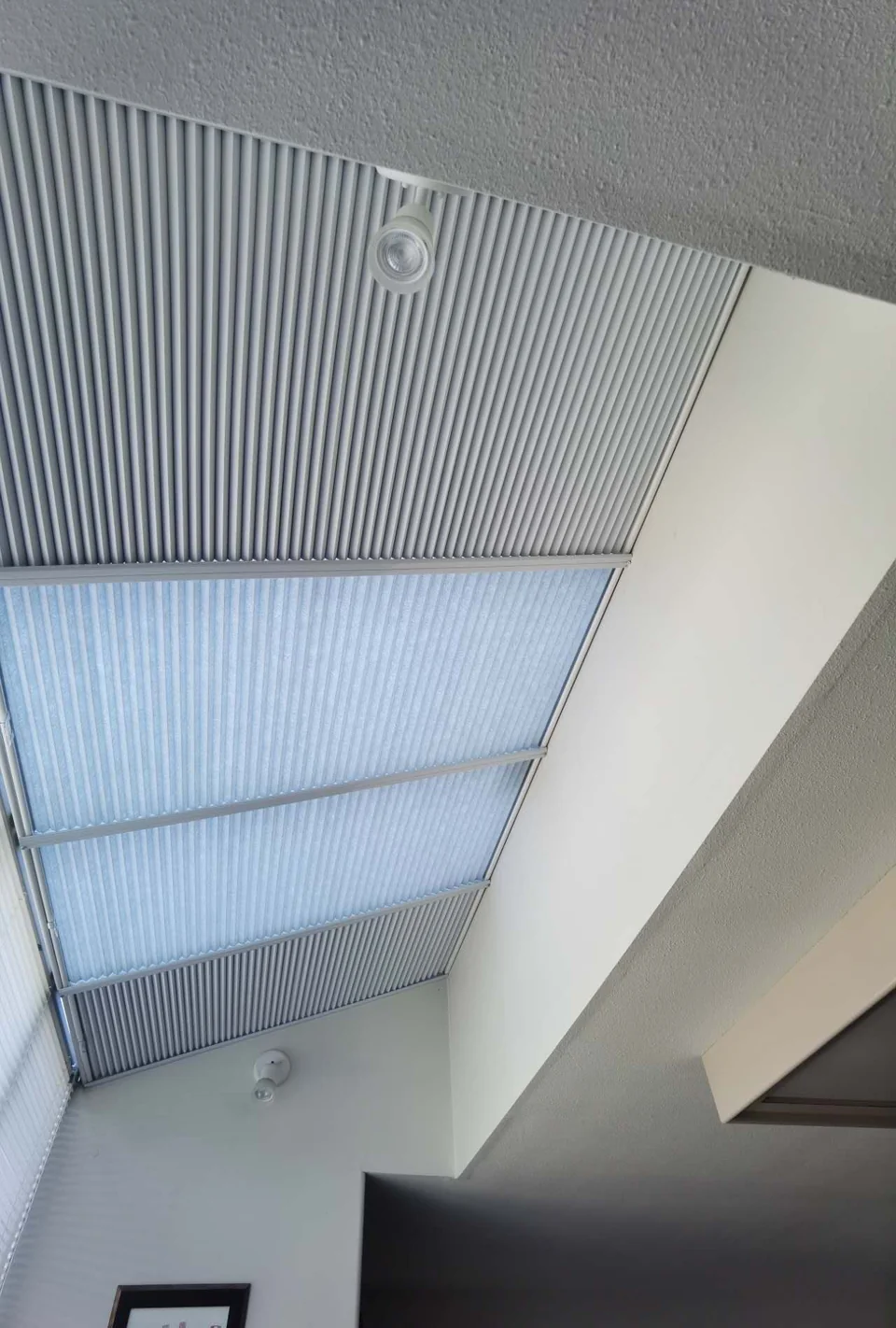 Manual honeycomb skylight shades with side channels, blackout end sections and light-filtering centre sections